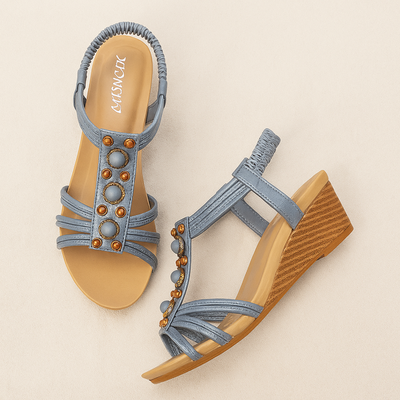 Blue wedge sandals with embellishments on a beige background