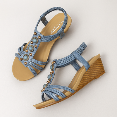 Pair of blue sandals with beige soles on a light gray background