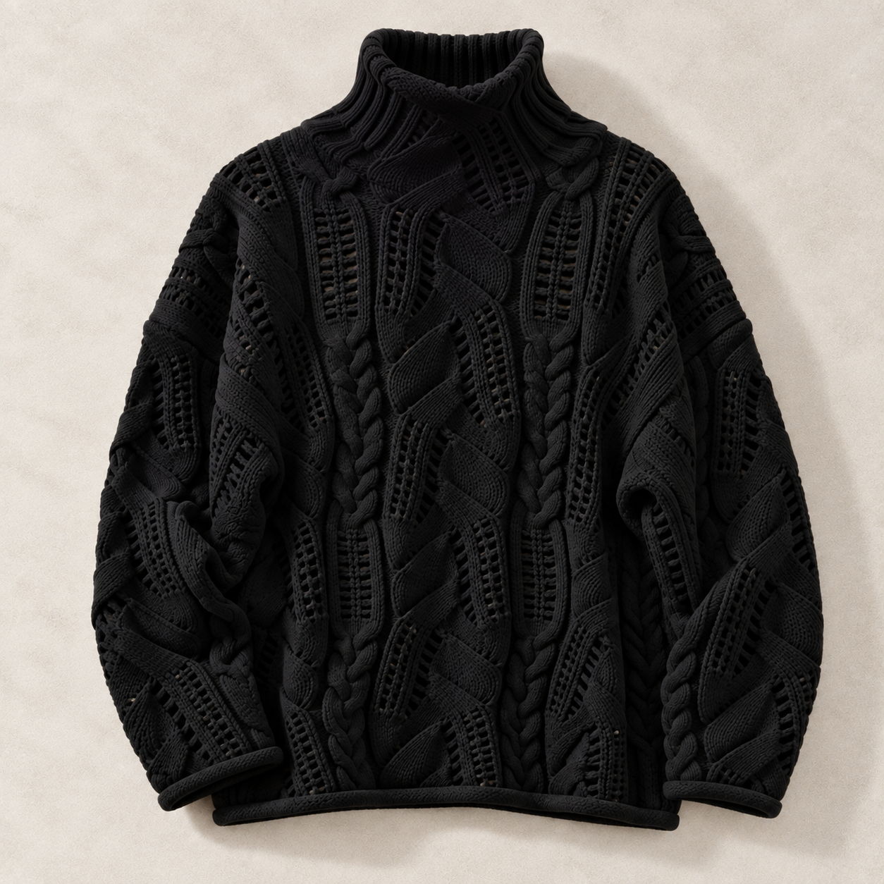 A black cable-knit turtleneck sweater with intricate textured patterns, laid flat on a light beige textured background.