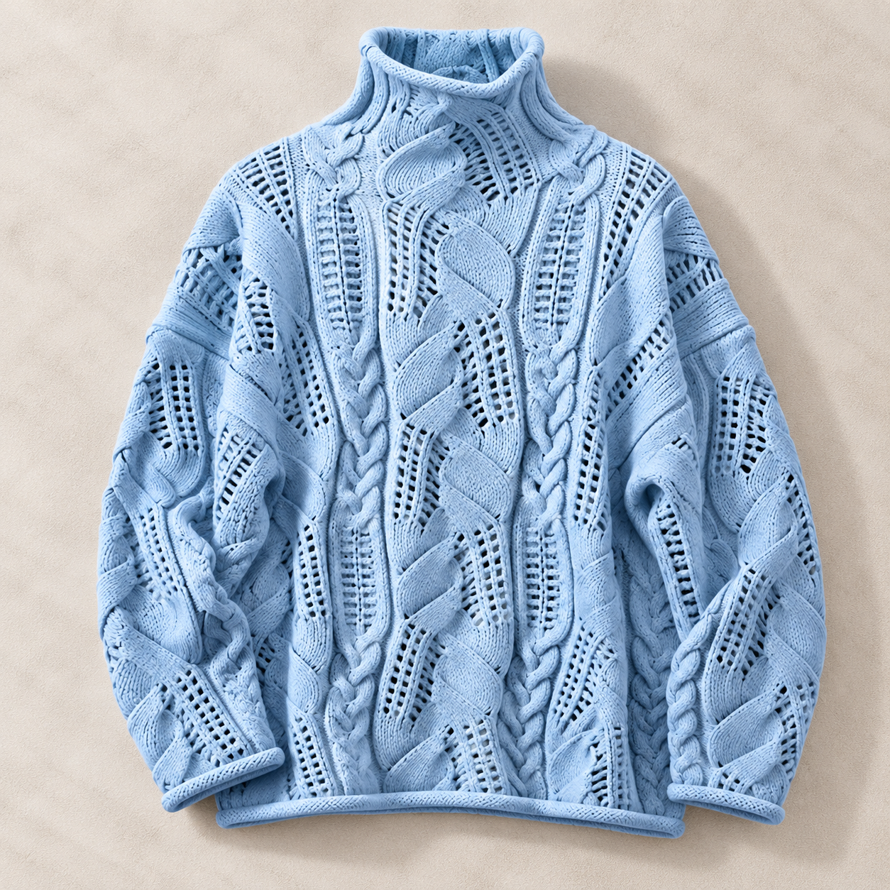 A light blue cable-knit mock-neck sweater with intricate openwork patterns, laid flat on a textured beige background.