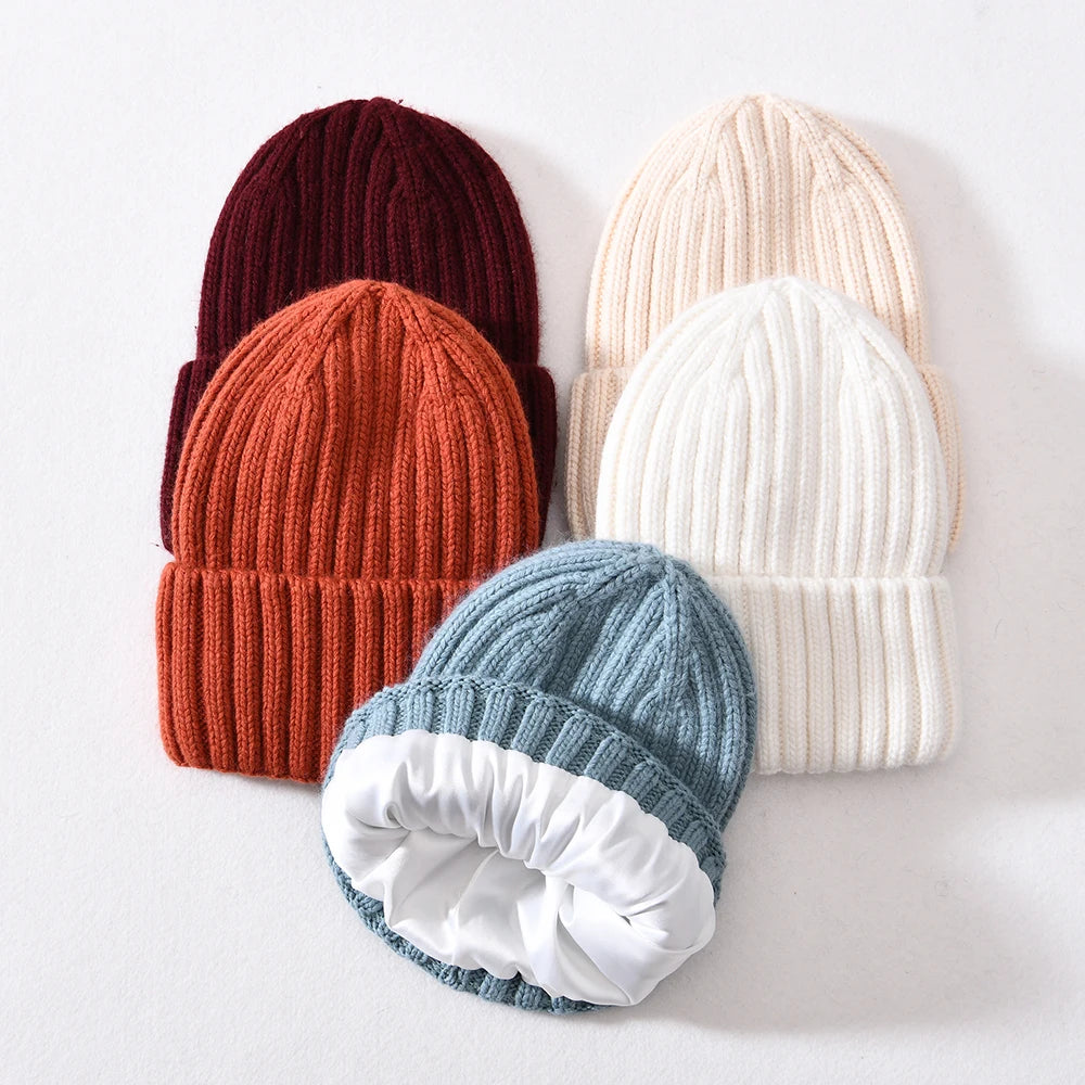 Five knit beanie hats in different colors on a light background