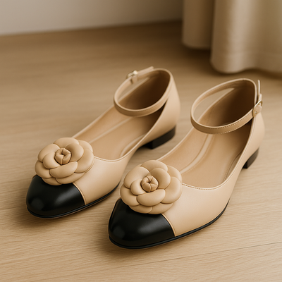 Pair of beige shoes with black toes and flower decorations on a wooden surface.