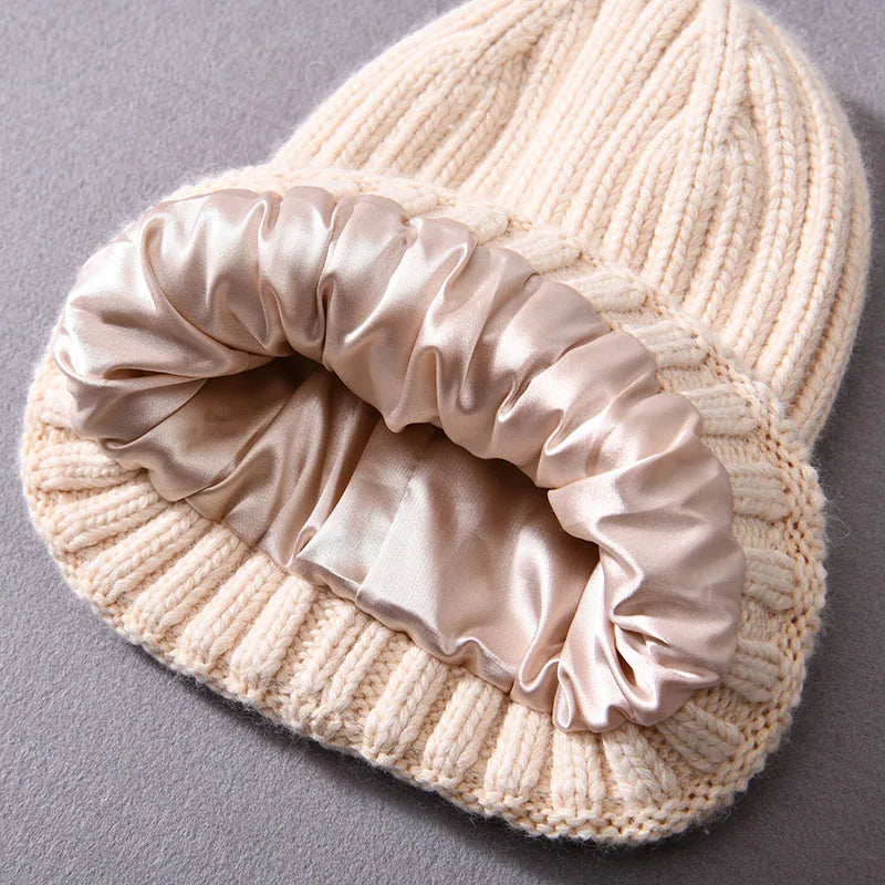 Knitted beige beanie with a satin scrunchie on a gray background