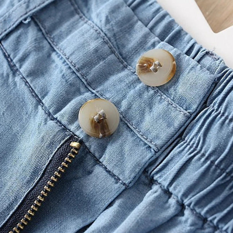 Close-up of a blue denim jacket with buttons and a zipper.