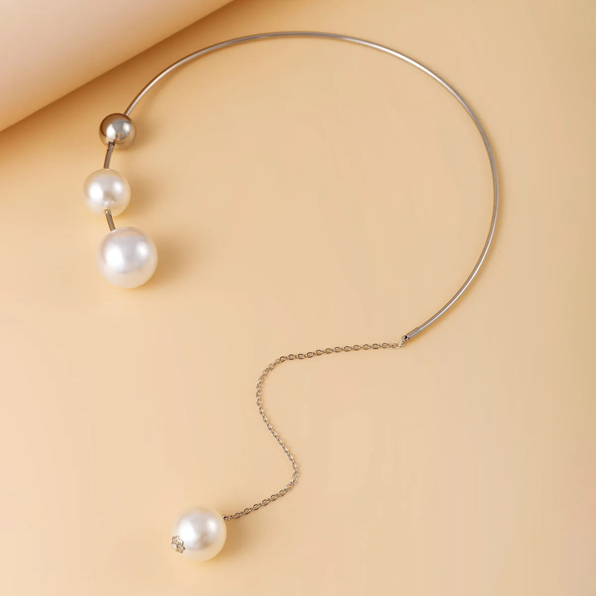 Pearl necklace with three pearls on a beige background