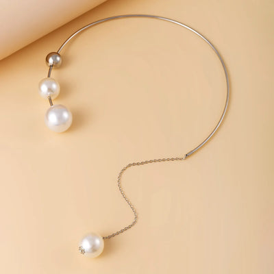 Pearl necklace with three pearls on a beige background