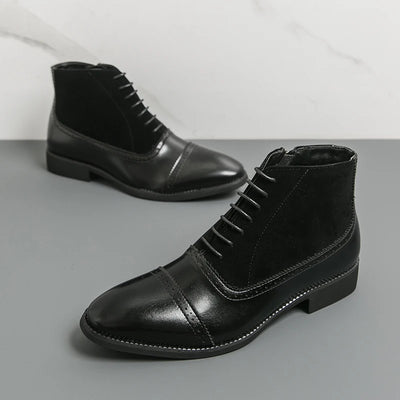 Pair of black leather boots on a gray surface with a white background