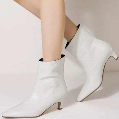 White ankle boots worn by a person on a light background