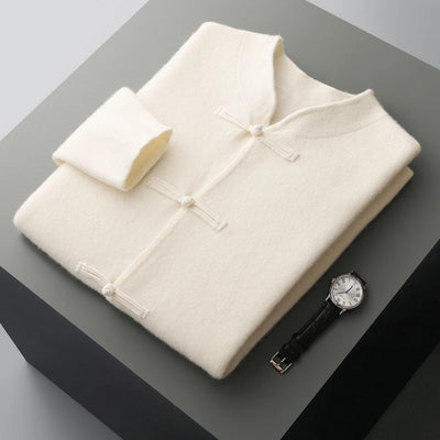 Folded cream-colored shirt and wristwatch on a gray surface