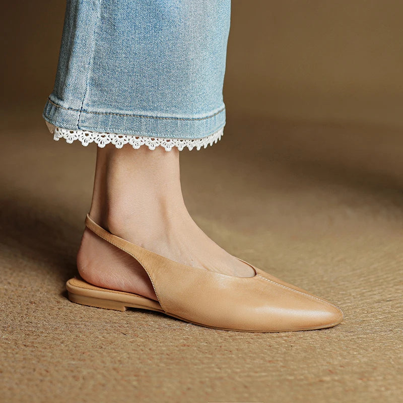 Beige flat shoe worn with light blue jeans on a brown background
