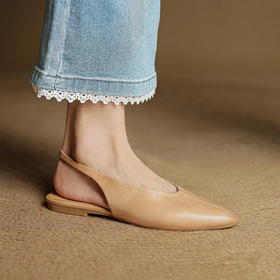 Beige flat shoe worn with light blue jeans on a brown background