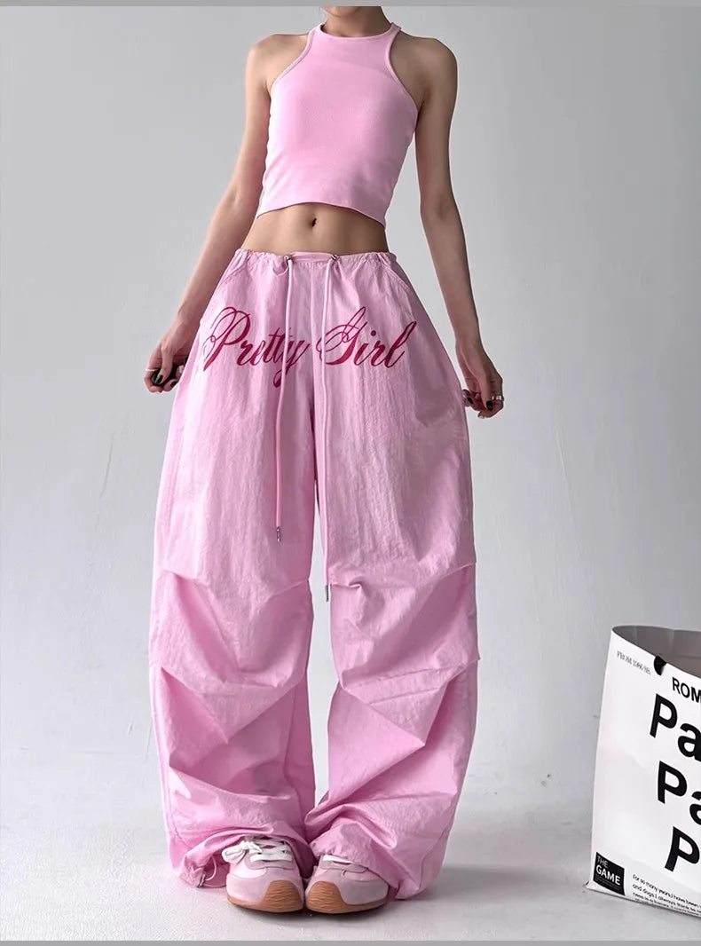 Person wearing a pink outfit with 'Pretty Girl' text on pants against a white background