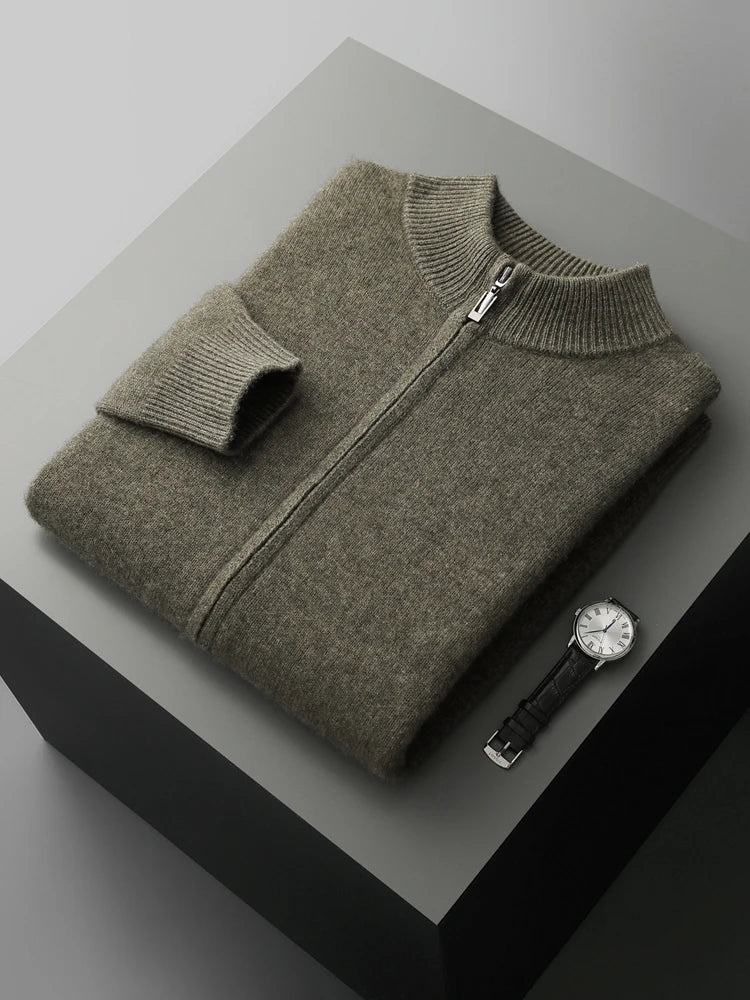 Folded gray sweater with a watch on a gray surface