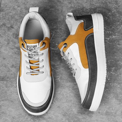 Pair of white sneakers with black and mustard accents on a gray surface
