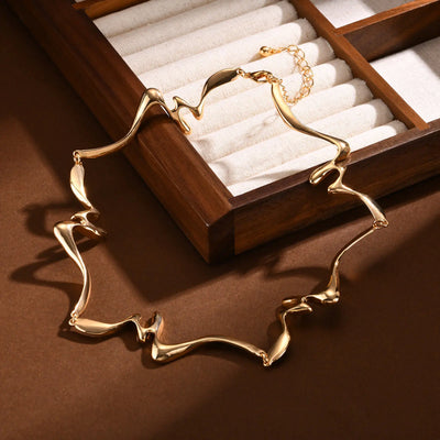Gold necklace on a brown surface with a wooden jewelry box in the background