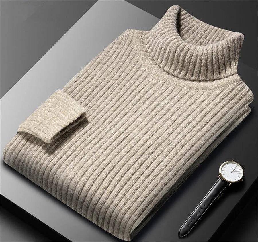 Folded beige sweater on a dark surface with a watch