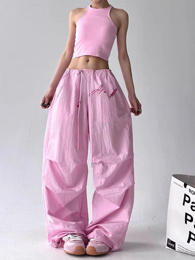 Person wearing a pink outfit with wide-leg pants and a crop top on a gray background.