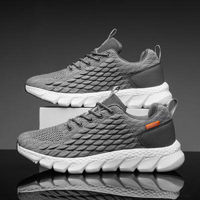 Gray and black athletic shoes with white soles on a reflective surface.