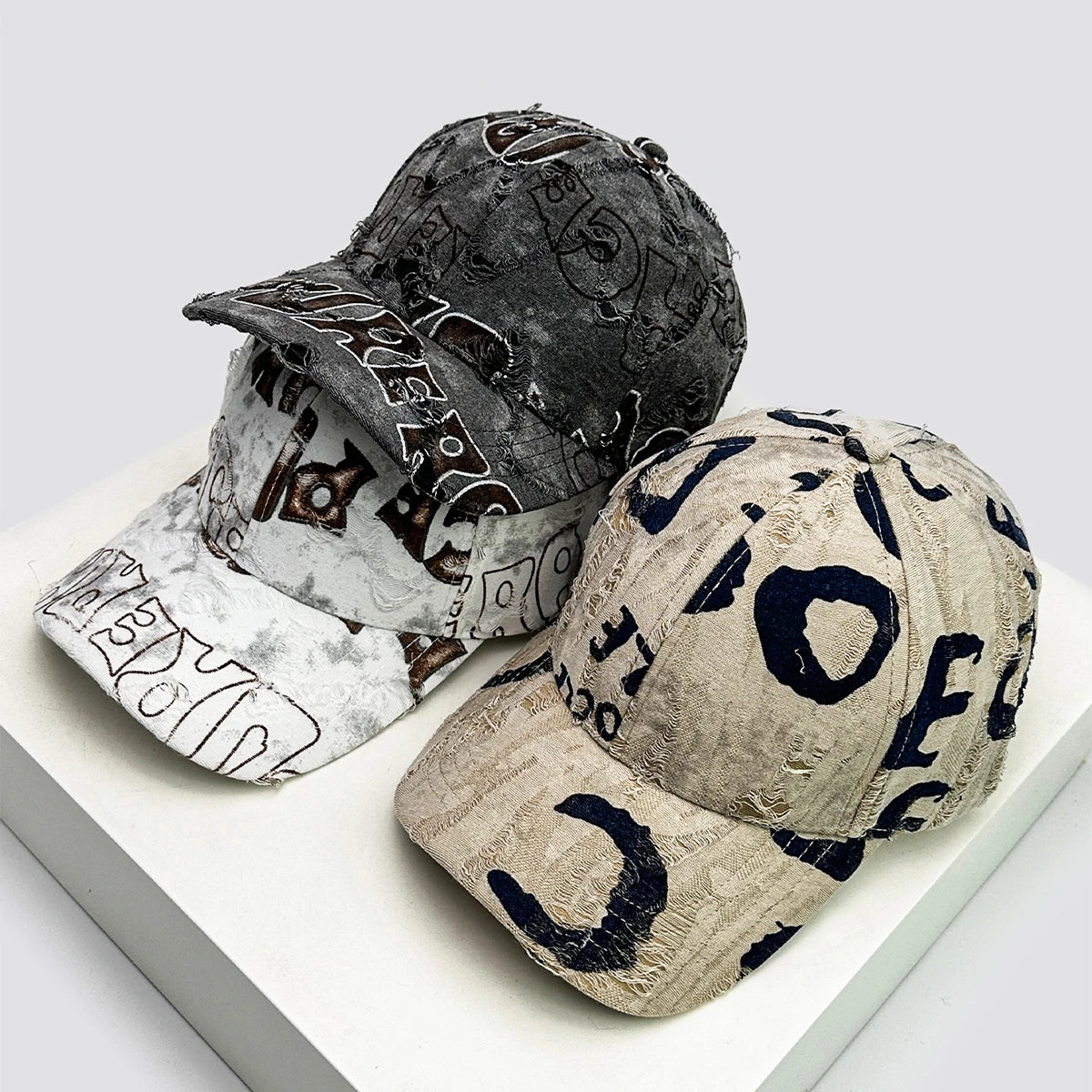Two distressed baseball caps with text design on a white surface