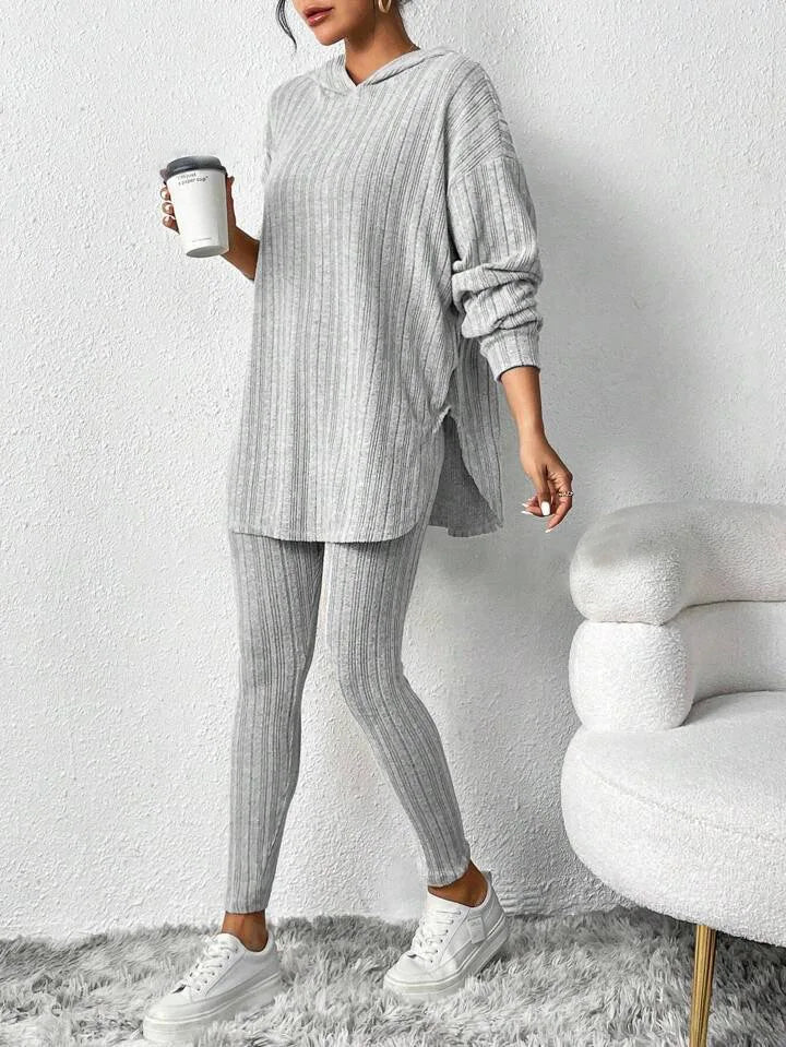 Person wearing a gray ribbed loungewear set holding a coffee cup against a white background.