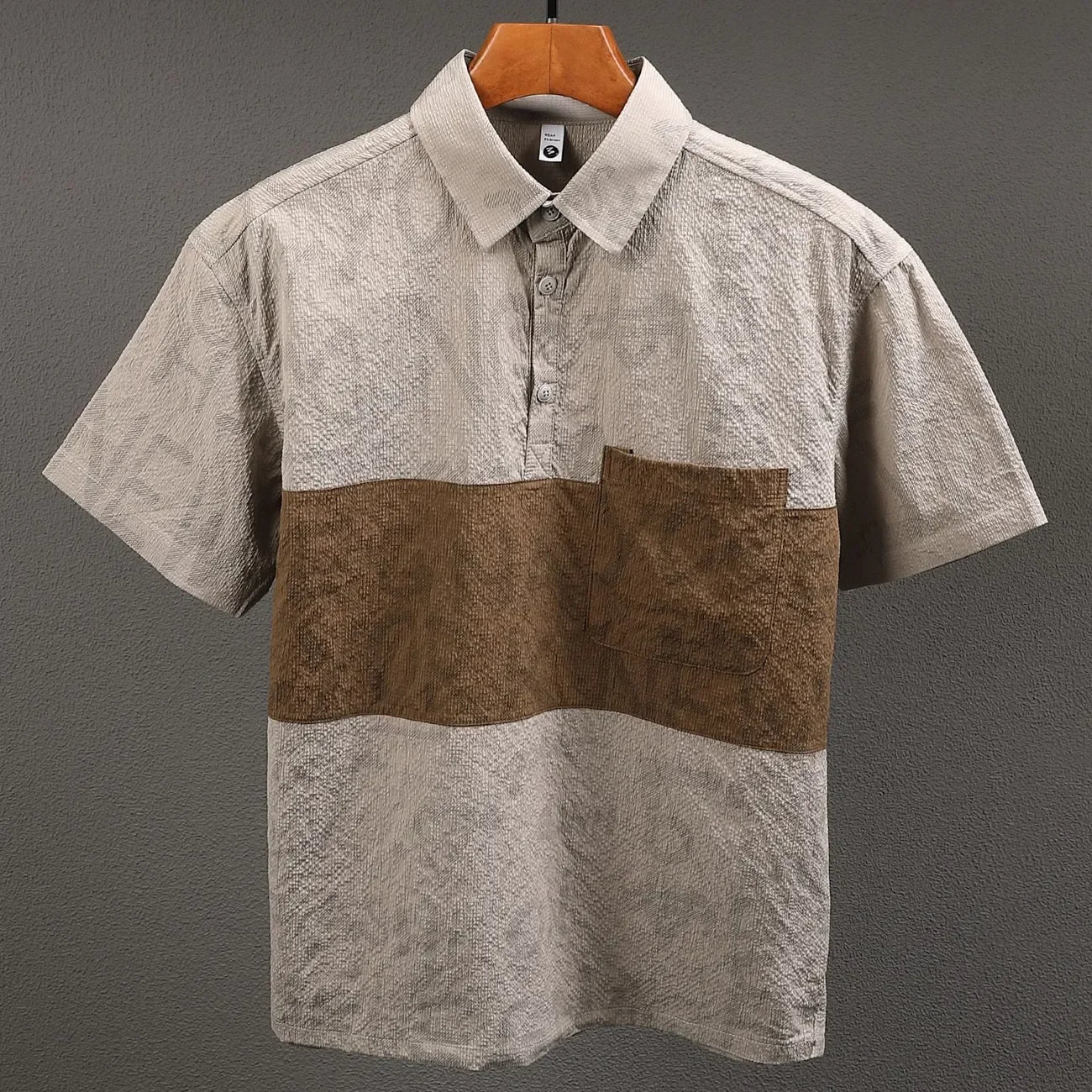 Short-sleeve shirt with brown and beige pattern on a hanger against a gray background
