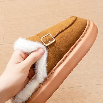 Brown slipper with white fur lining held by a hand on a beige background