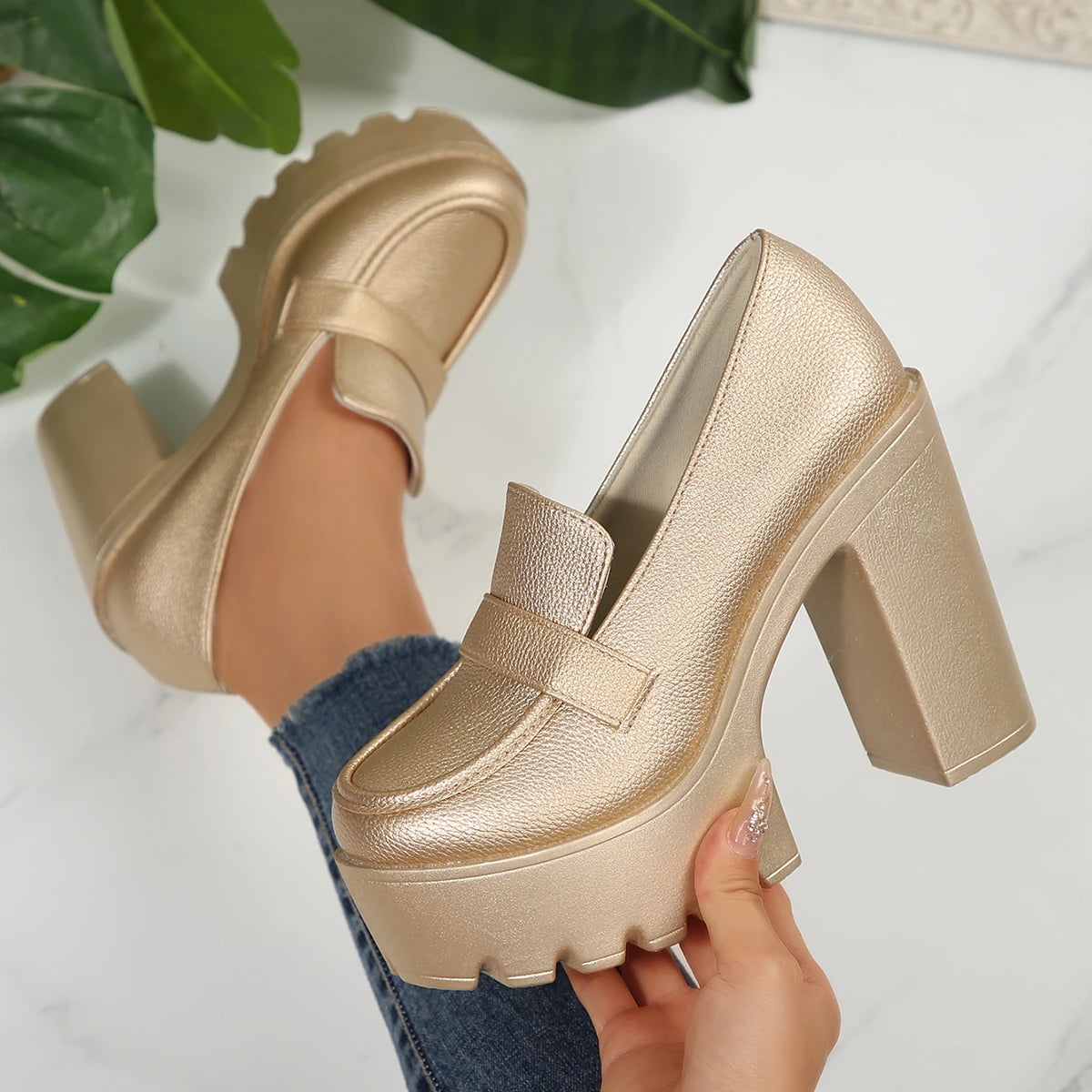 Gold platform shoes being held with a white background