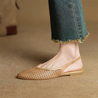 Beige flat shoe worn with blue jeans on a neutral background