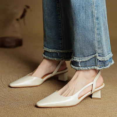 White slingback shoes worn with blue jeans on a brown surface