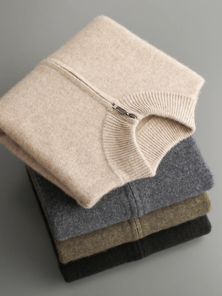 Stack of folded sweaters in beige, gray, and brown on a gray background