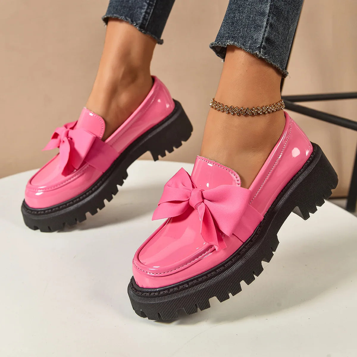 Pink loafers with bows on a neutral background