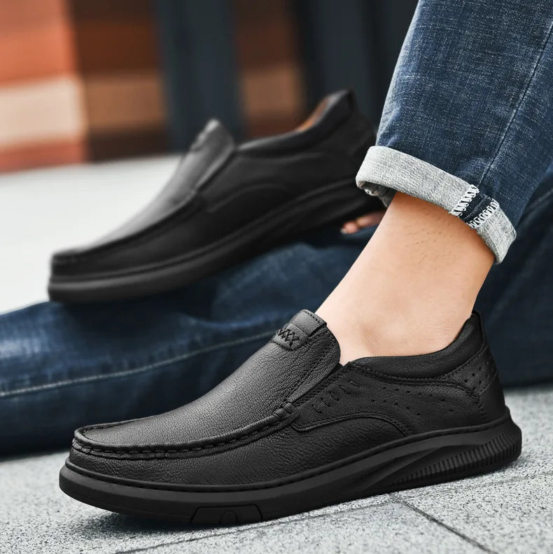 Black leather shoes worn with rolled-up jeans on a blurred background