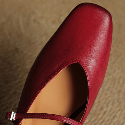 Red leather shoe with a strap on a textured surface