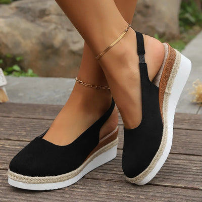 Black wedge sandals with jute sole on a wooden surface