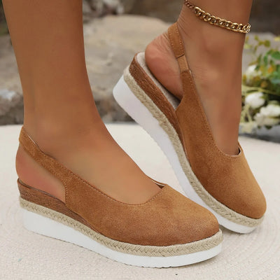Brown wedge sandals with white soles worn by a person on a blurred natural background