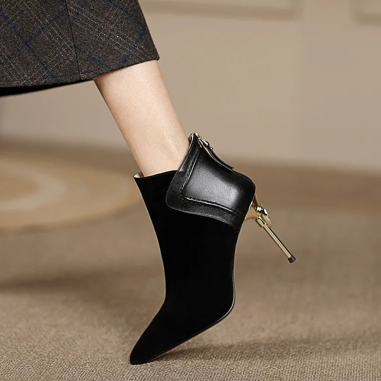 Black ankle boot with a gold heel on a neutral background