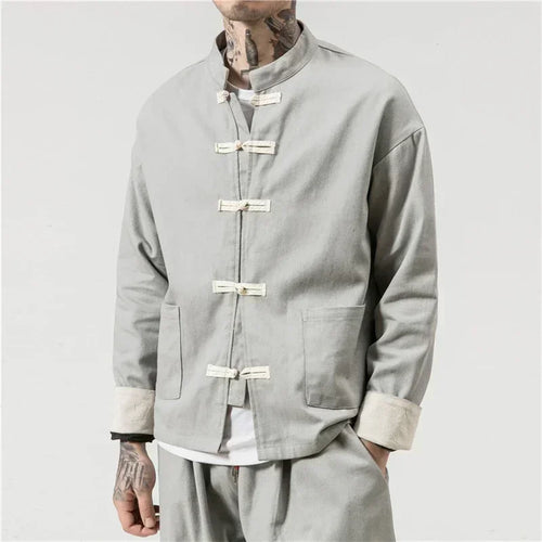 Person wearing a light gray traditional jacket with button details on a plain background