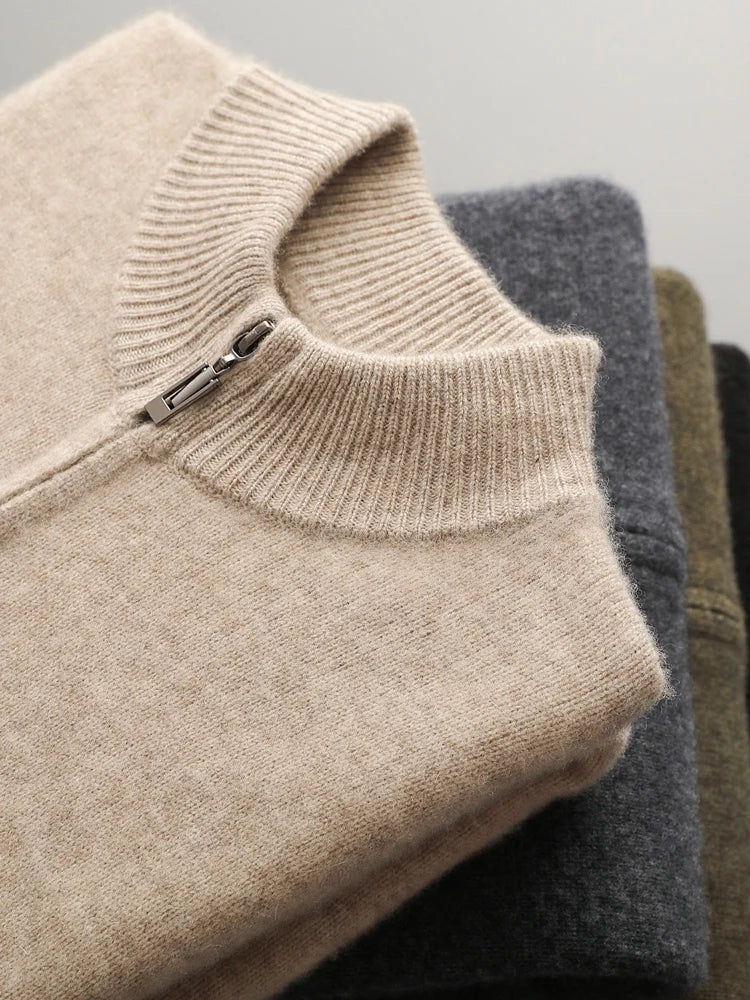 Stack of folded sweaters in beige, gray, and brown on a light gray background