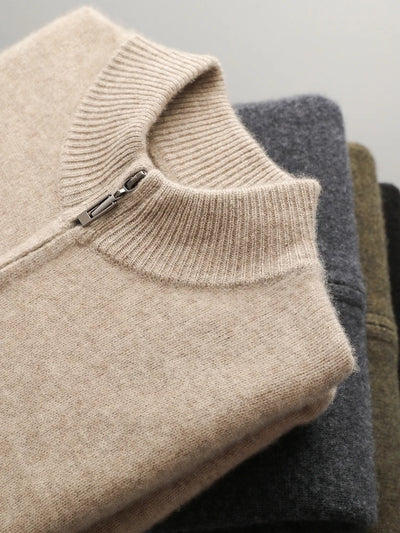 Stack of folded sweaters in beige, gray, and brown on a light gray background