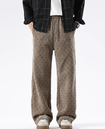 Person wearing brown checkered pants with a black jacket on a white background