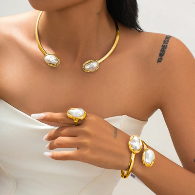 Gold jewelry set with necklace, ring, and bracelet on a model against a neutral background