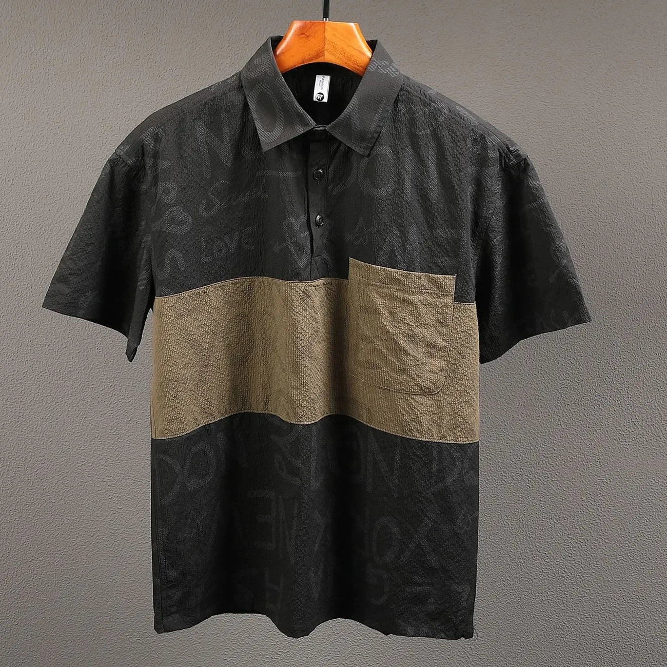 Two-tone black and beige shirt on a hanger against a gray background
