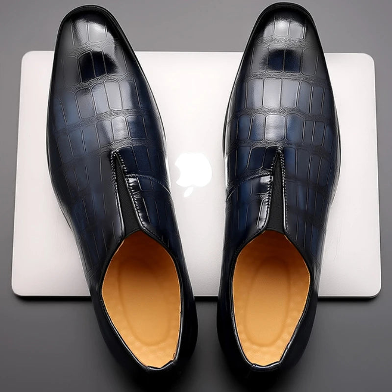Pair of black dress shoes with a textured pattern on a white platform.