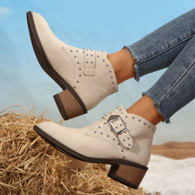 White studded boots with brown soles worn by a person on a blurred natural background