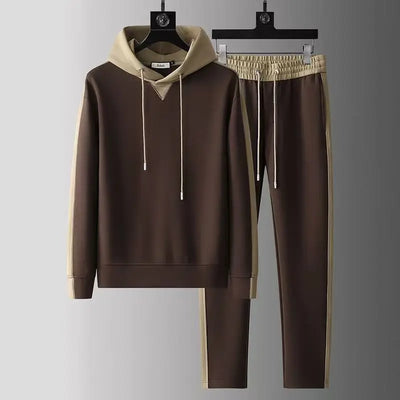 Brown hoodie and pants set with beige accents on hangers against a gray background