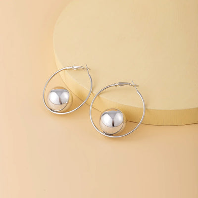 Silver hoop earrings with spherical ends on a beige background
