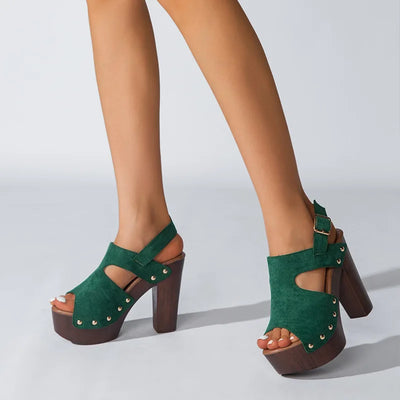 Green suede platform sandals with brown block heels on a light gray background