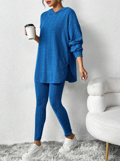 Person wearing a blue ribbed lounge set holding a coffee cup against a white wall.