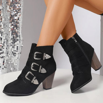 Black ankle boots with decorative buckles on a neutral background