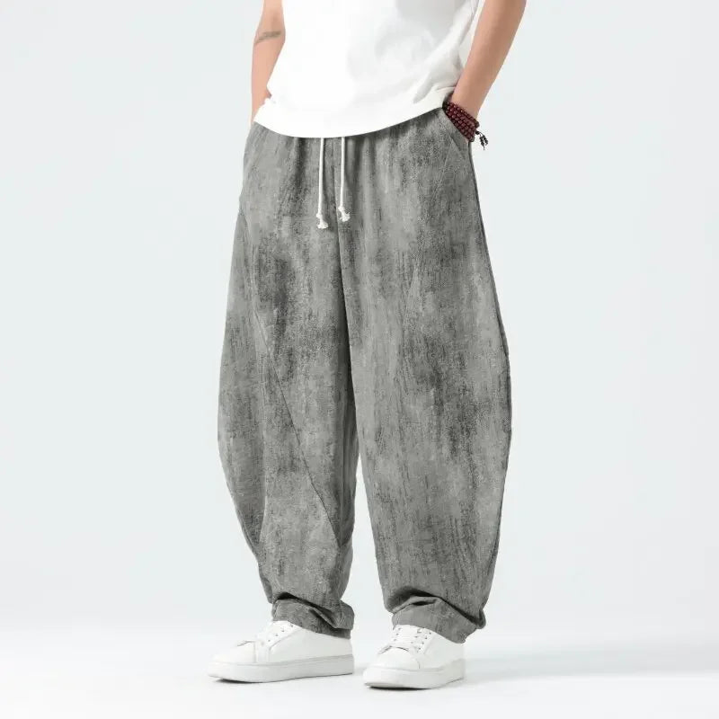 Person wearing gray baggy pants and white shoes on a light gray background